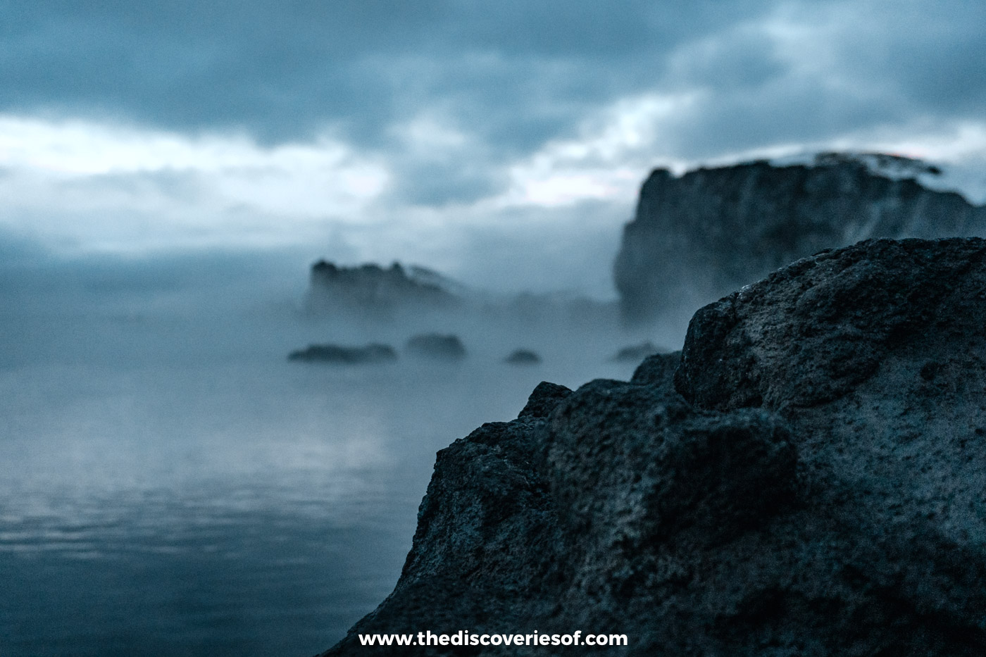 Mist drifting over the geothermal water and dark lava rocks at Sky Lagoon near Reykjavik in winter