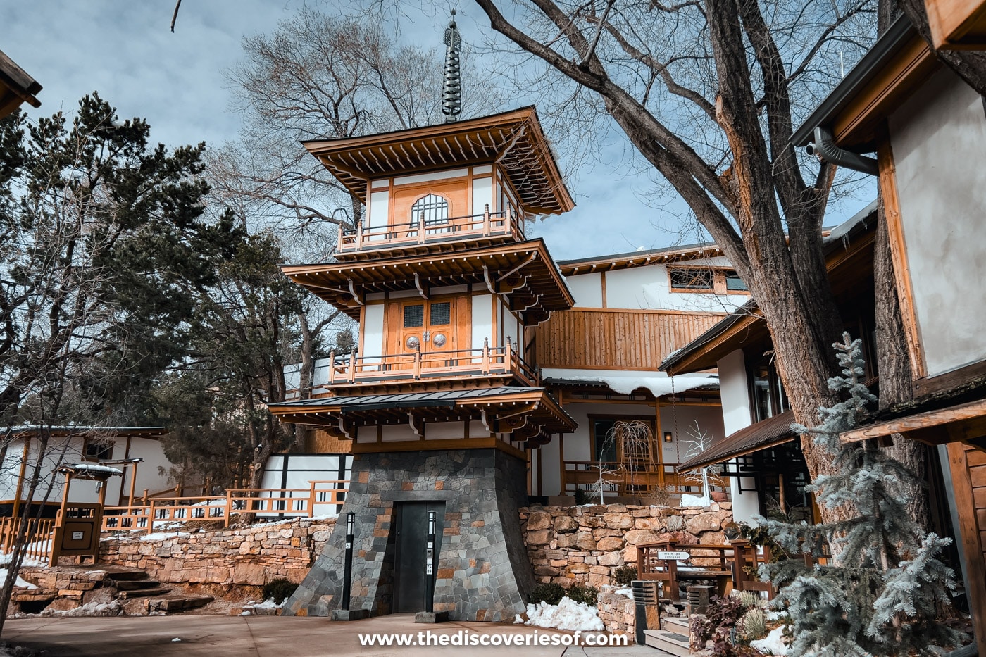 Japanese-style wooden tower and stone walls among bare trees and snow at Ten Thousand Waves, Santa Fe