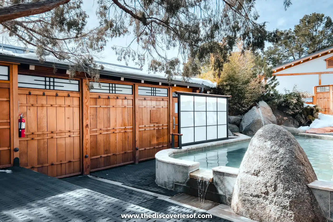 Wooden gate, boulders and a steaming outdoor pool surrounded by snow at Ten Thousand Waves spa, Santa Fe