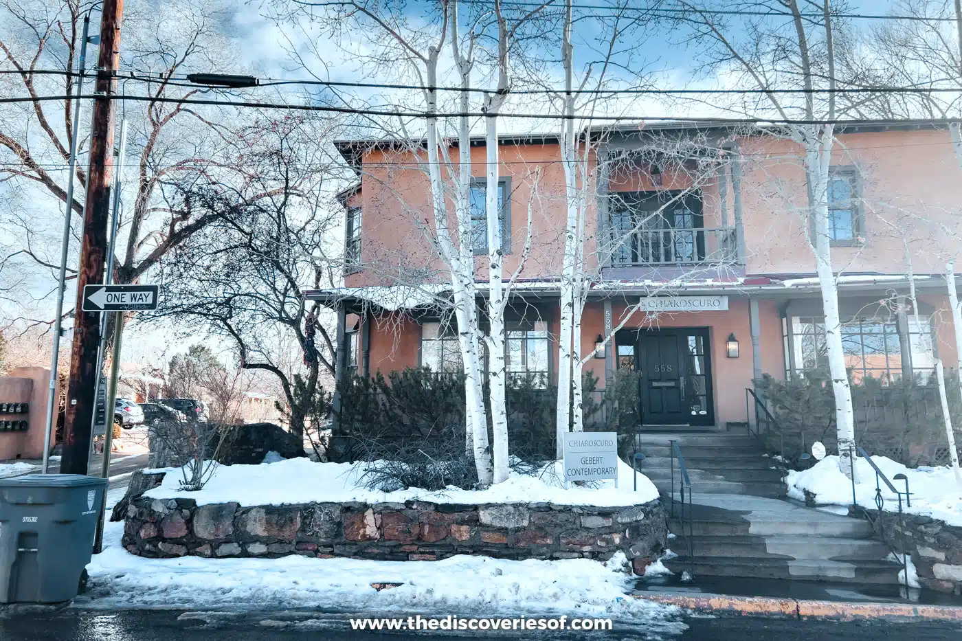 Two-storey adobe house with silver birch trees and snow on the ground in Santa Fe, New Mexico