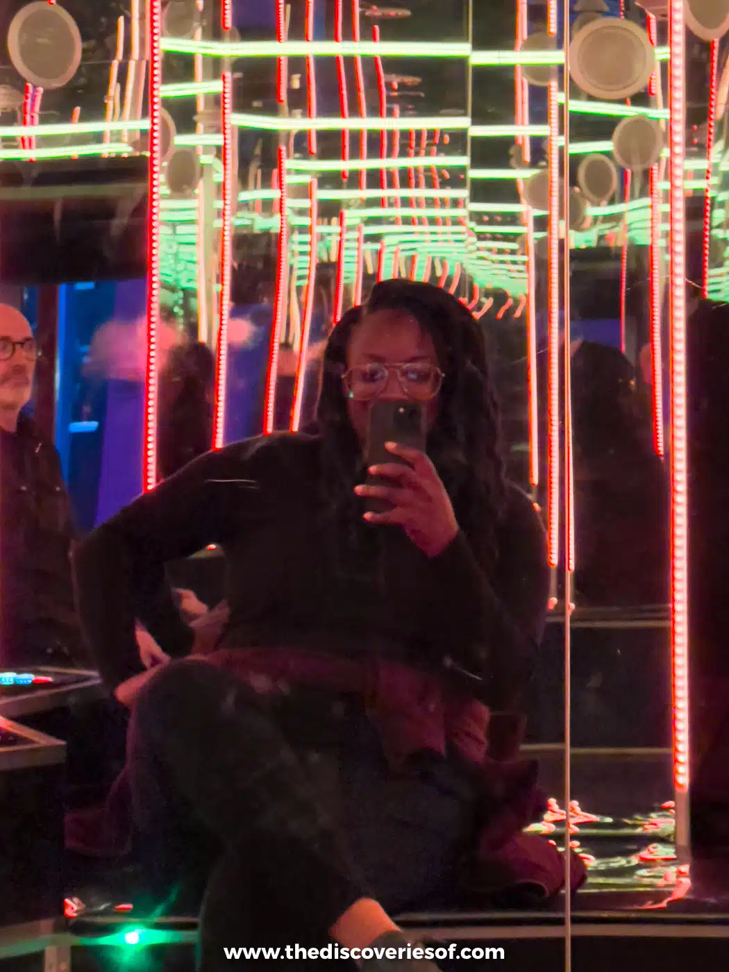 Julianna taking a selfie in a mirror room lined with neon lights at Meow Wolf's House of Eternal Return, Santa Fe