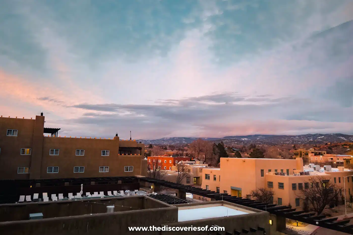 Dusk over the flat adobe rooftops of downtown Santa Fe, New Mexico, with hills on the horizon