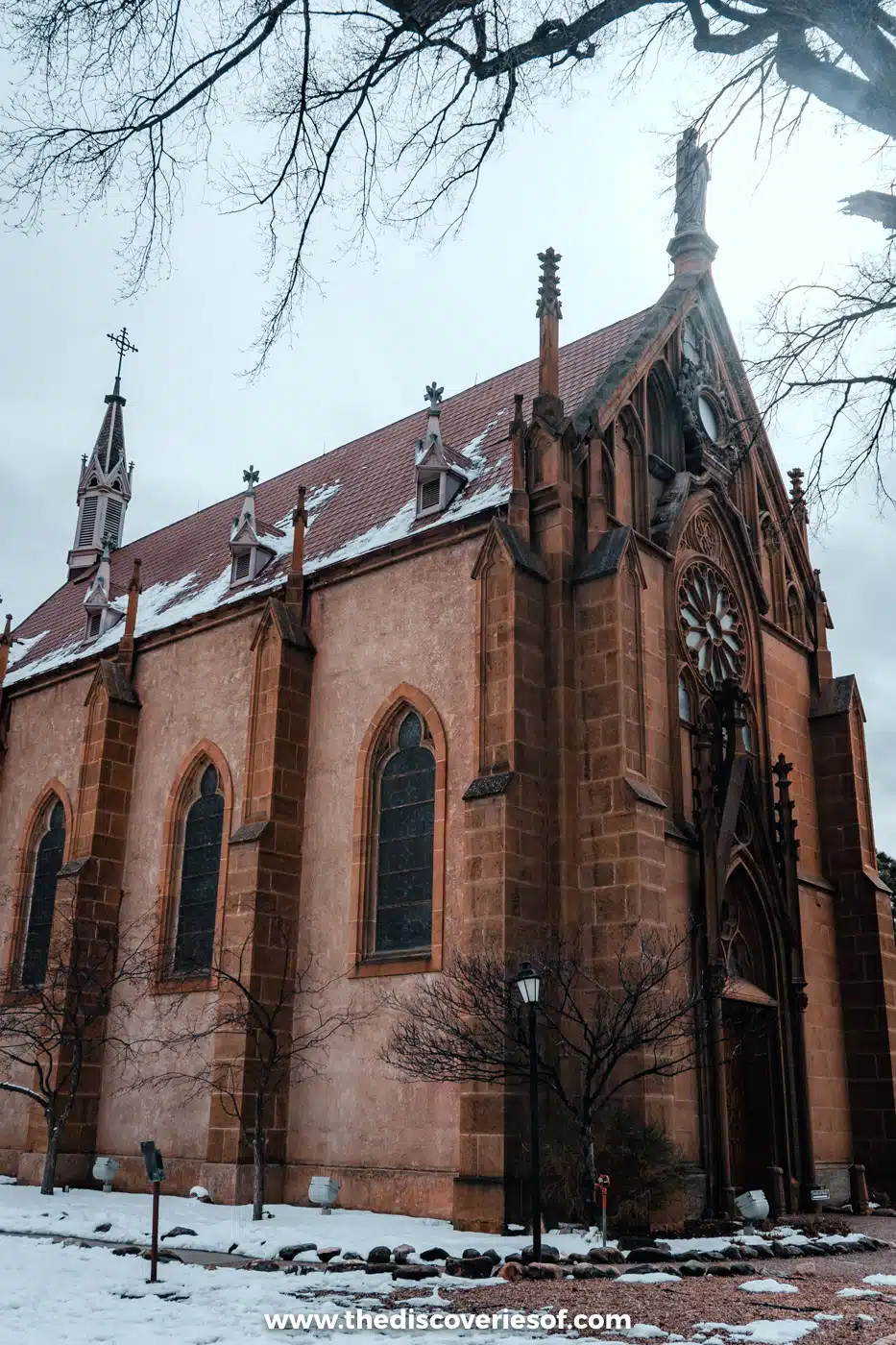 Gothic Revival stone facade and spires of Loretto Chapel with snow on the ground, Santa Fe