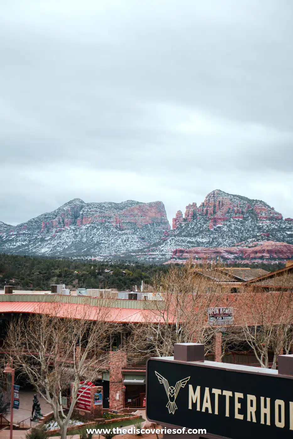 Snow-covered red rocks above the Matterhorn Inn sign in Uptown Sedona