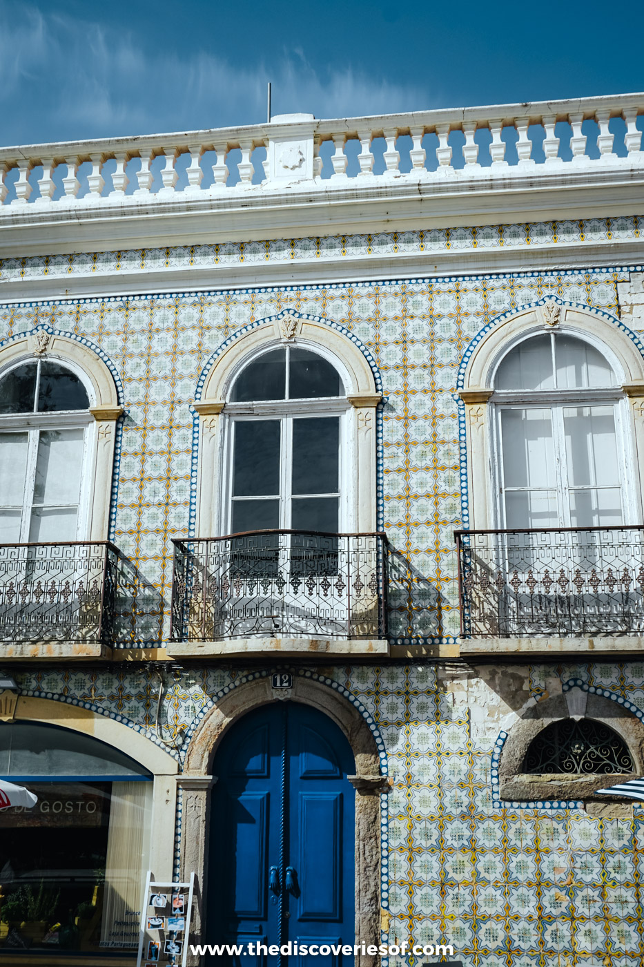 Blue and yellow tiled façade with arched windows, wrought iron balconies and a blue door in Tavira's old town