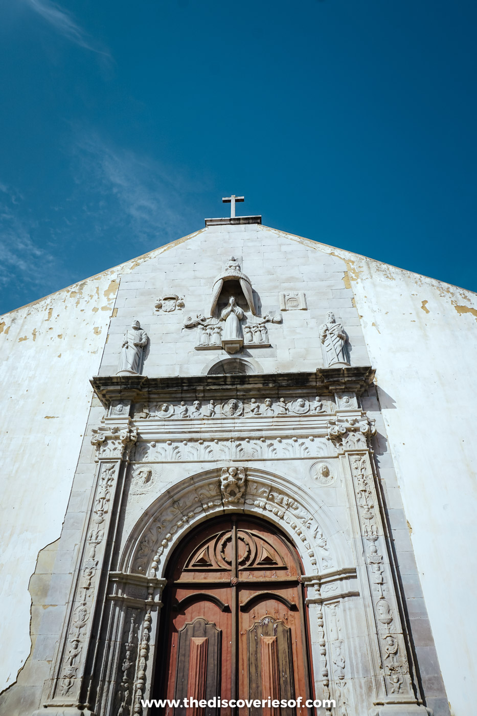 The carved stone Renaissance portal of the Igreja da Misericórdia in Tavira, with statues of Our Lady of Mercy and two saints above the wooden door