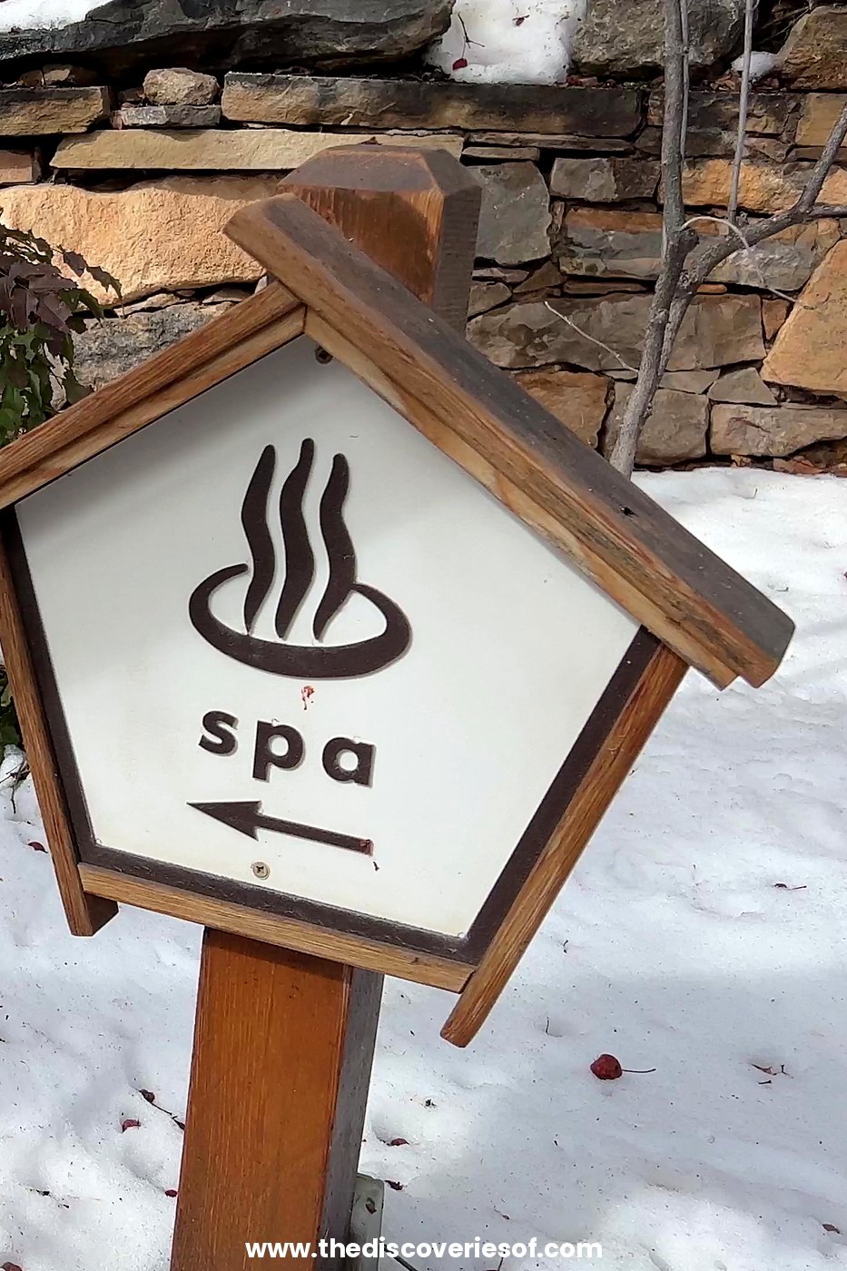Wooden spa sign with an onsen symbol and an arrow in the snow at Ten Thousand Waves mountain spa, Santa Fe