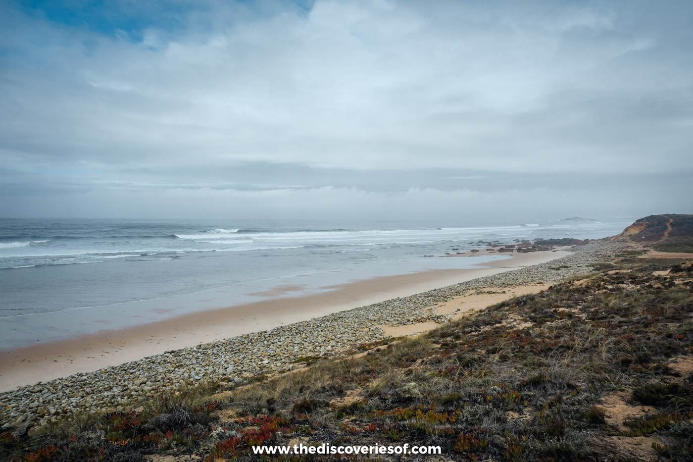 A long empty sandy beach and grey Atlantic surf below dunes on the Alentejo coast south of Praia do Malhão