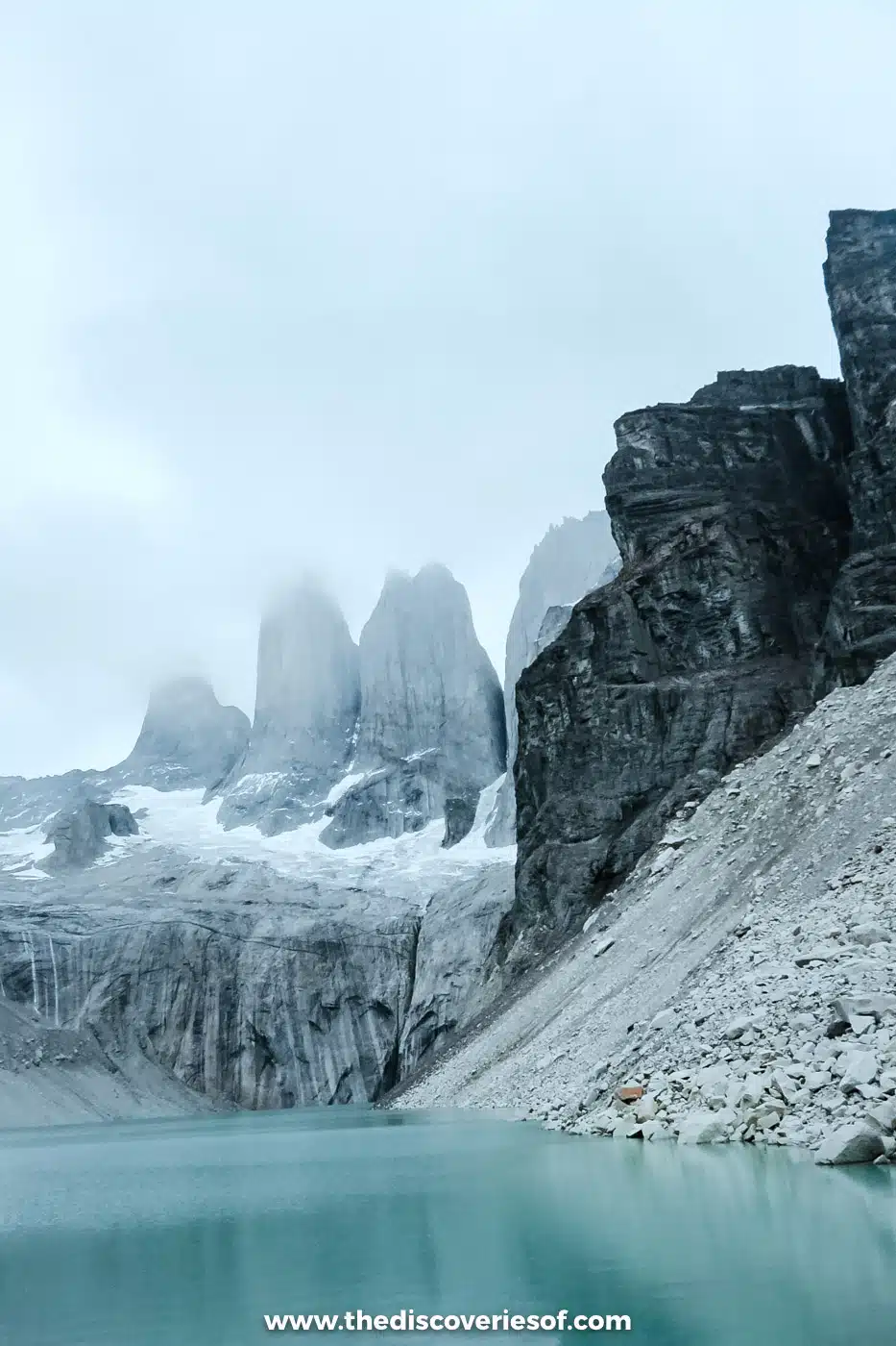 The Torres del Paine towers and their lagoon beneath a dark cliff, Chile