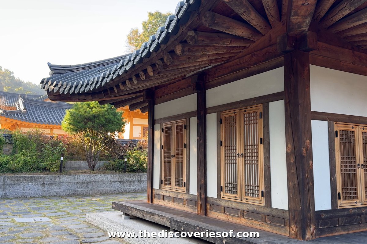 A restored hanok with latticed wooden doors and white walls beside a stone-paved courtyard at Tradition Resort Gurume, Andong