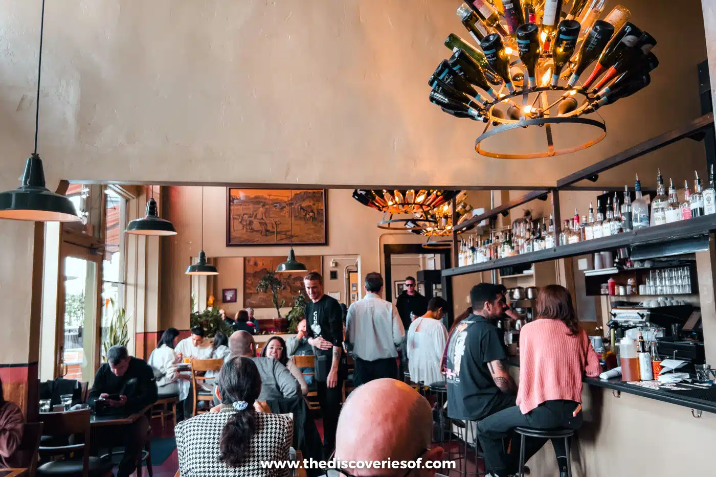 Diners and a busy bar under a bottle chandelier at Cup Cafe in Hotel Congress, Tucson