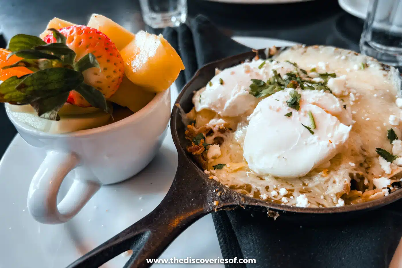 A poached egg in a cast-iron skillet with a cup of fresh fruit at Cup Cafe, Tucson