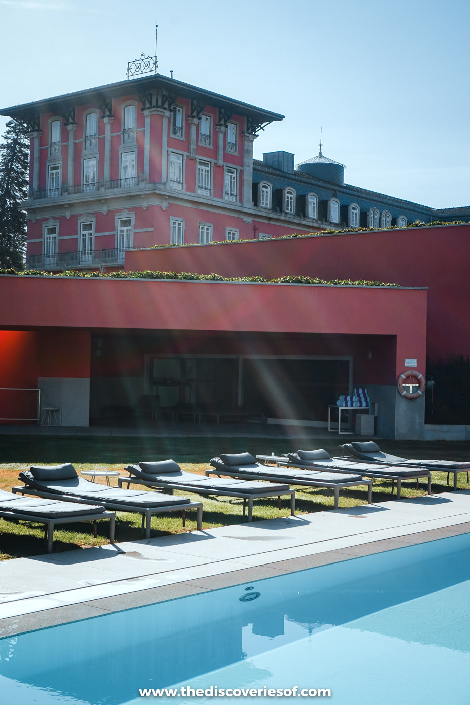 Sun loungers beside the outdoor pool at Vidago Palace, with the pink façade of the spa hotel behind