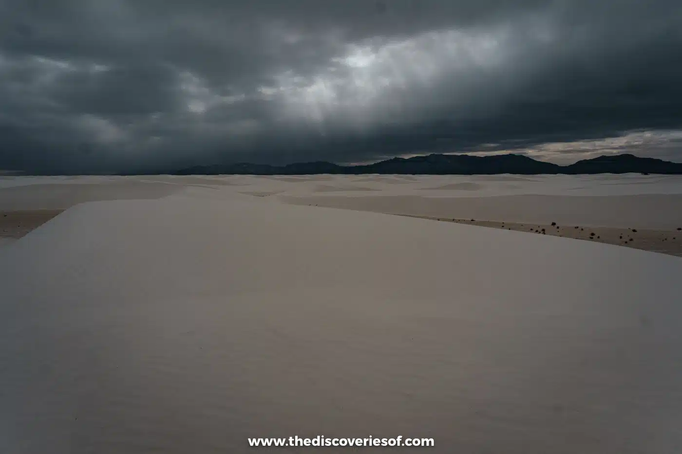 Dark rain clouds gathering over the empty white dunes and mountains of White Sands National Park