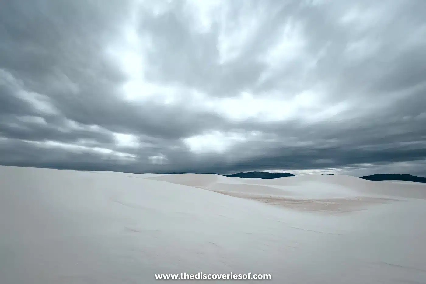 Wide open white gypsum dunes under a dramatic sky of swirling storm clouds at White Sands National Park