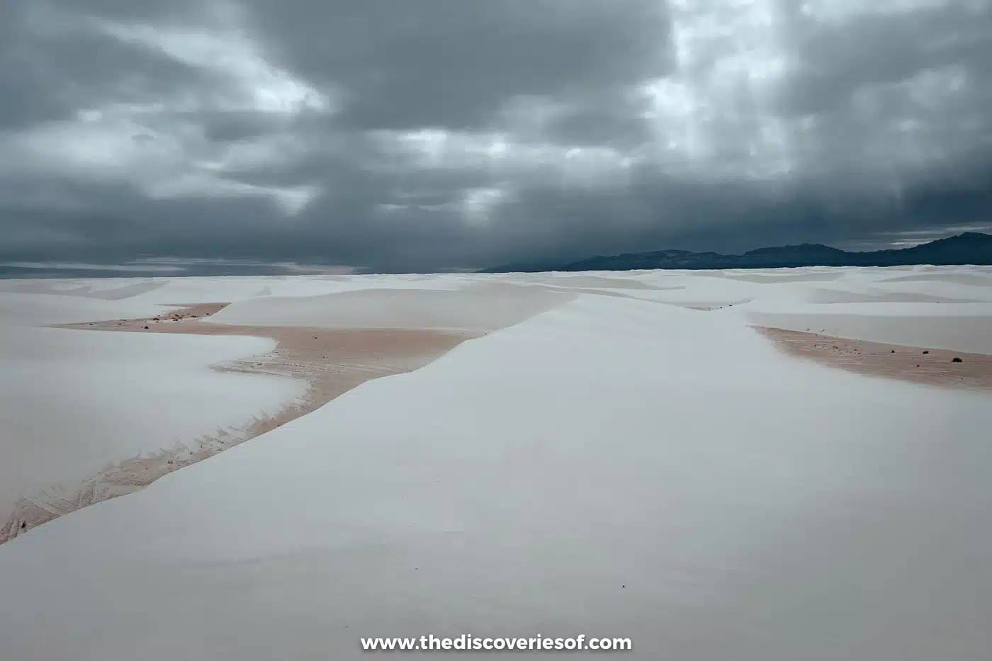 White gypsum dune ridges with pale brown sandy hollows stretching towards mountains at White Sands National Park